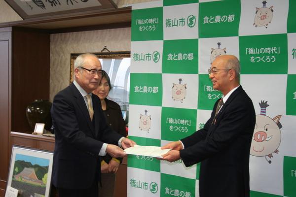 市長が篠山市食育推進計画策定委員会より食育推進計画の書類を受け取っている写真